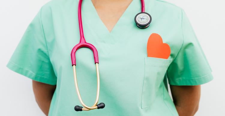 Medic in scrubs with stethoscope and red paper heart