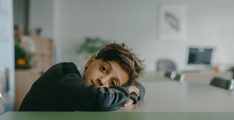 Sad boy rests head on table