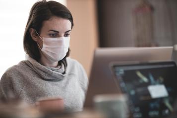 woman wearing a mask sitting at computer 
