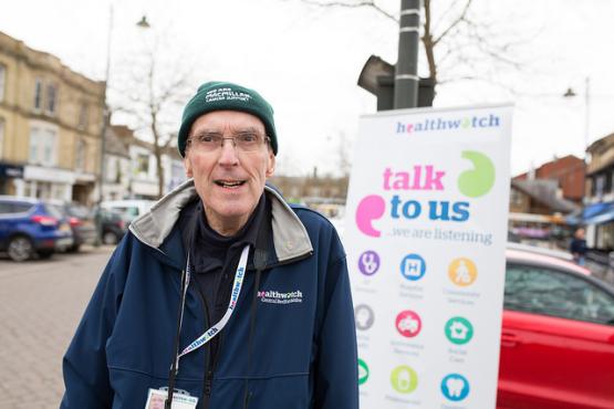 Man standing infront of Healthwatch banner Man standing infront of Healthwatch banner
