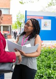Photo shows two women talking outside of a hospital. 